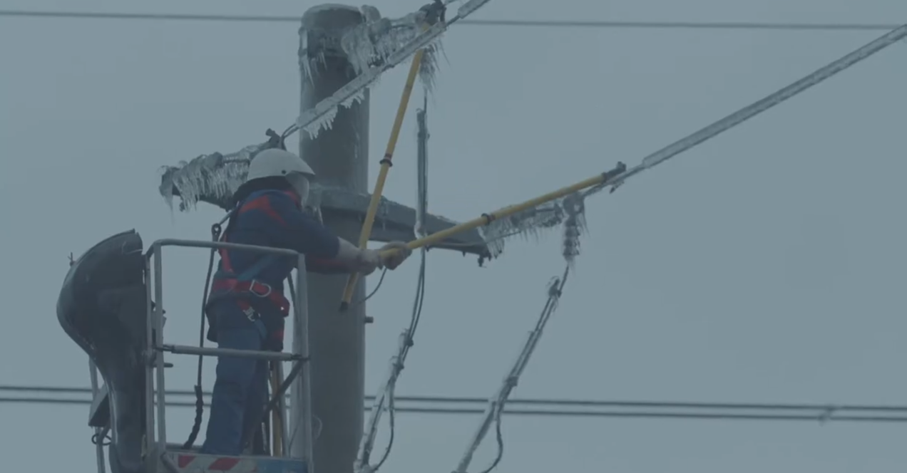E-Distribuție Muntenia employee, in the nacelle, at height, removing the ice from an overhead power line