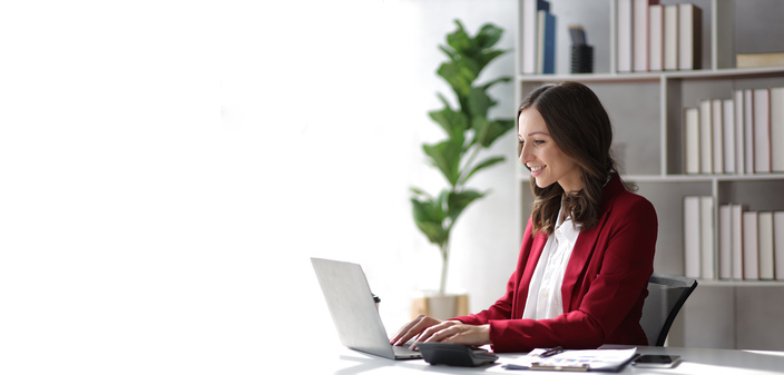 Femeie aflată într-un birou dintr-un spațiu office, aflată la birou, în timp ce lucrează la laptop
