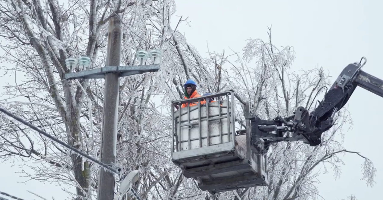 Angajat E-Distribuție Muntenia care lucrează în condiții de iarnă, dintr-o nacelă, la înălțime, lângă o linie electrică aeriană înghețată