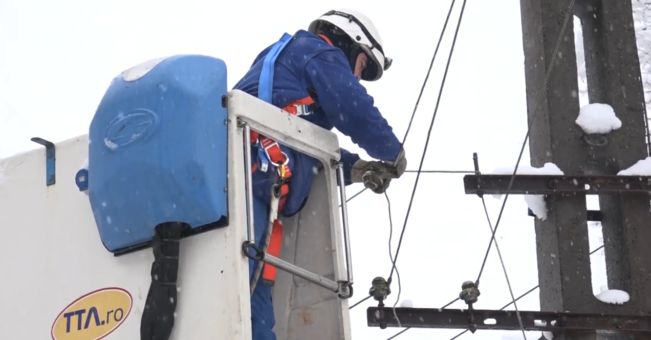 Angajat E-Distribuție Banat intervine, dintr-o nacelă, pentru remedierea unei avarii la o linie electrică aeriană acoperită cu zăpadă