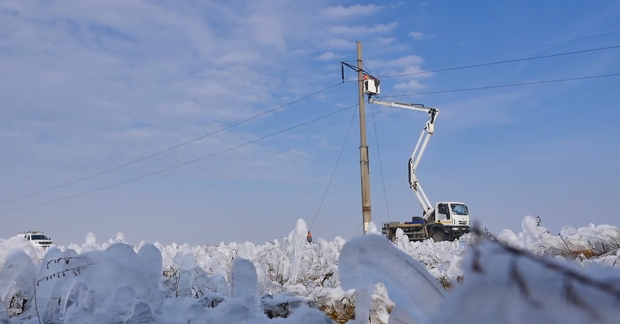 Câmp din Dobrogea acoperit cu zăpadă, iar în fundal o mașină de intervenție a E-Distribuție 