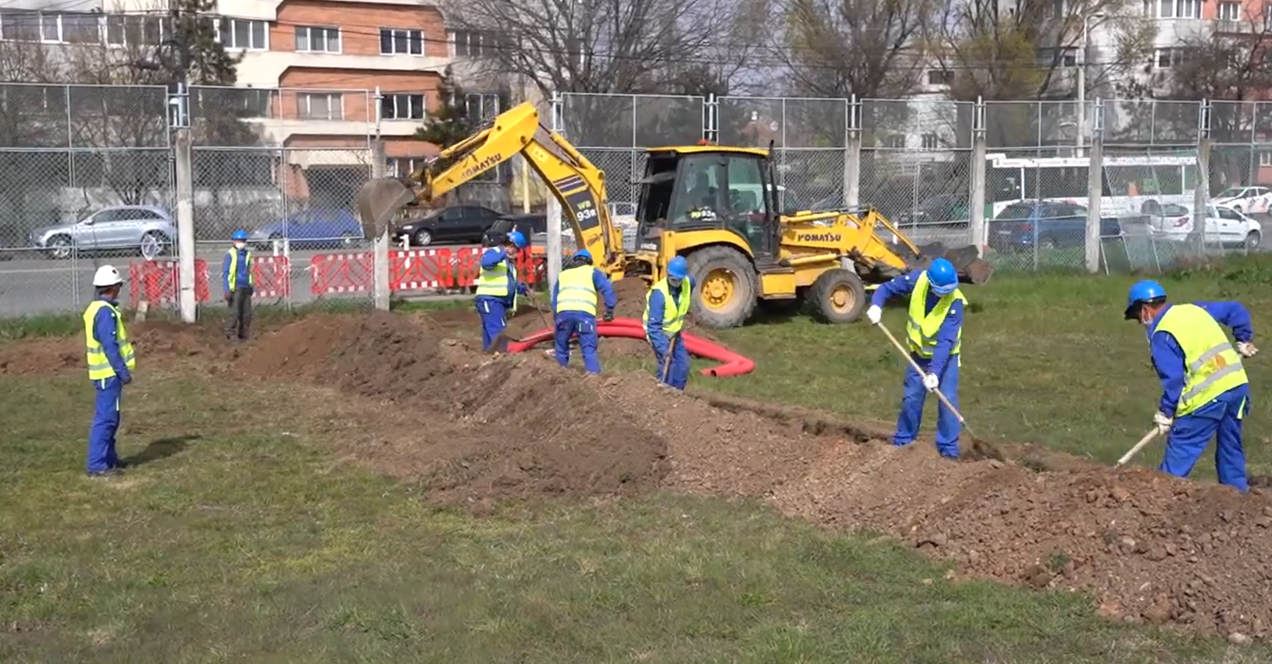 Muncitori un excavator lucrează pe șantierul deschis pentru racordarea Spitalului Militare de Campanie din Constanța